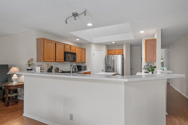 kitchen with stainless steel appliances, light countertops, wood finished floors, a peninsula, and a textured ceiling