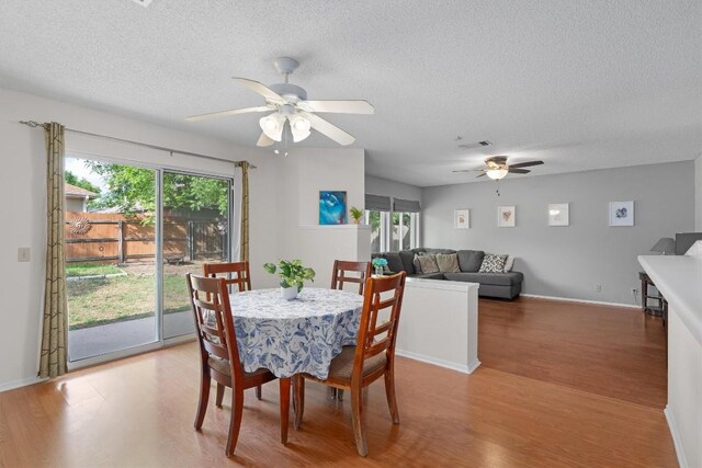 dining room featuring visible vents, a ceiling fan, wood finished floors, and a textured ceiling