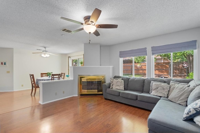 living room featuring a ceiling fan, a textured ceiling, and visible vents
