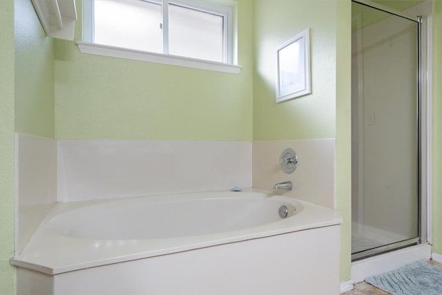 full bathroom with a shower stall and a bath