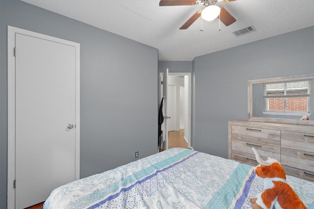 bedroom featuring visible vents, a textured ceiling, and ceiling fan