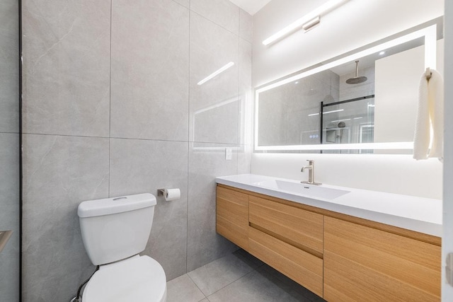 full bath with tile patterned flooring, toilet, vanity, a walk in shower, and tile walls