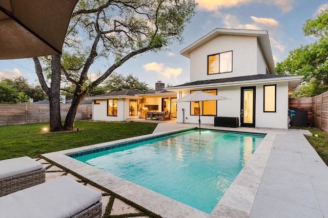 back of house at dusk with a fenced in pool, outdoor lounge area, a yard, cooling unit, and a patio area