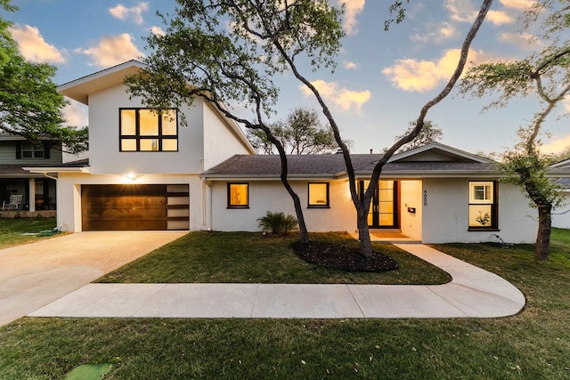 view of front of home with an attached garage, a yard, and stucco siding