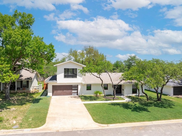view of front of home with an attached garage, concrete driveway, a front yard, and stucco siding