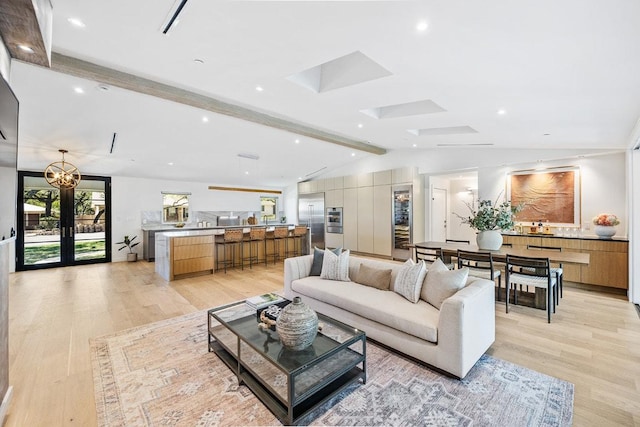 living area with vaulted ceiling with skylight and light wood-type flooring