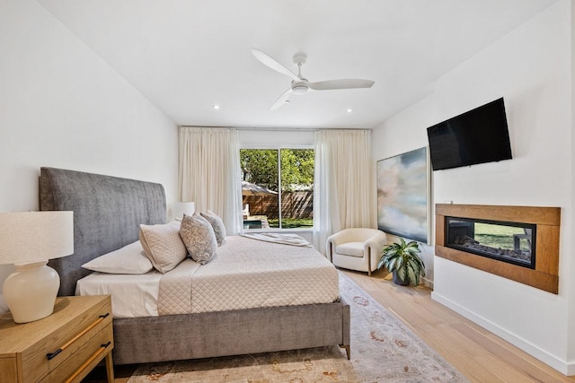 4000 Greystone Dr, Austin, TX 78731 - bedroom featuring wood finished floors, a multi sided fireplace, a ceiling fan, recessed lighting, and baseboards
