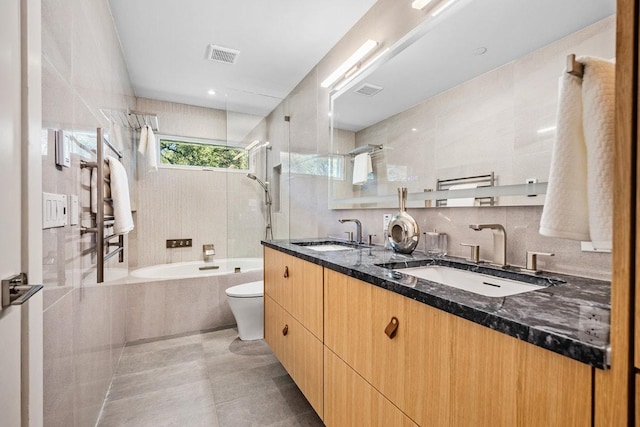 full bath featuring tiled shower / bath combo, toilet, a sink, and visible vents