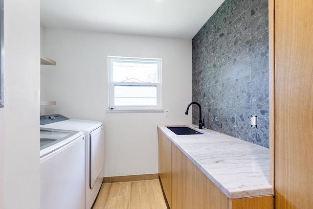 laundry area with washer and clothes dryer, laundry area, a sink, baseboards, and light wood-style flooring