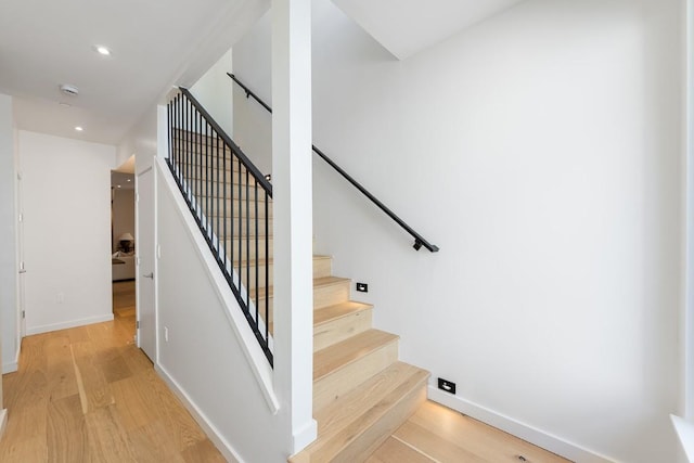stairway featuring baseboards, wood finished floors, and recessed lighting