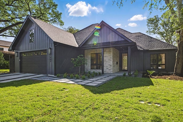 view of front facade with board and batten siding, a shingled roof, a front yard, and driveway