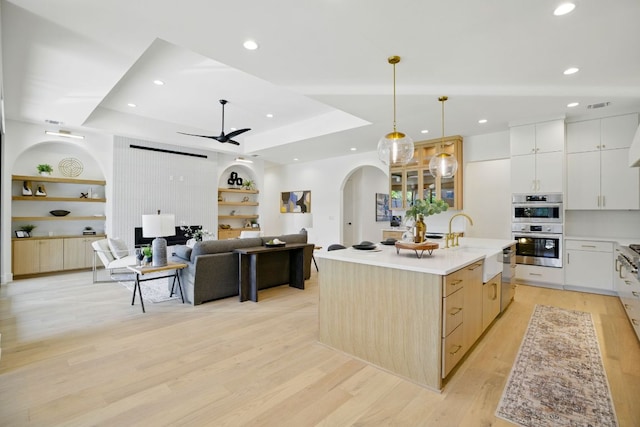 kitchen with arched walkways, appliances with stainless steel finishes, built in shelves, a sink, and a ceiling fan
