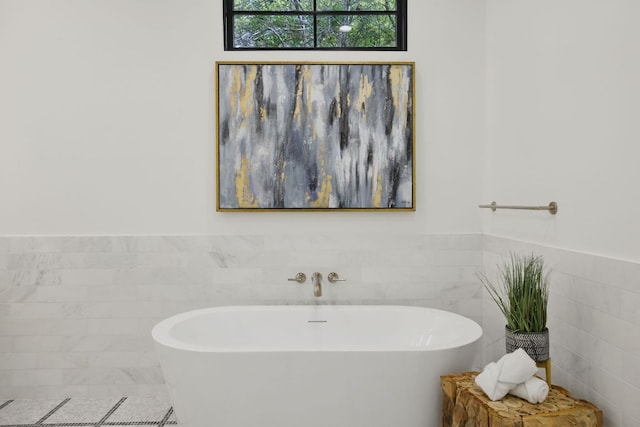 bathroom featuring tile walls, a freestanding bath, and a wainscoted wall