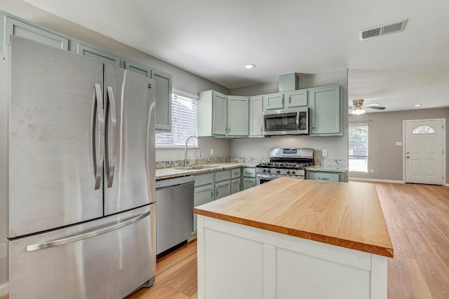 6603 Krollton Dr, Austin, TX 78745 - kitchen with appliances with stainless steel finishes, a sink, light wood-type flooring, wood counters, and healthy amount of natural light