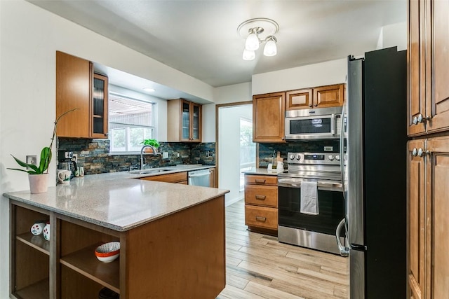kitchen with brown cabinetry, a sink, appliances with stainless steel finishes, and tasteful backsplash