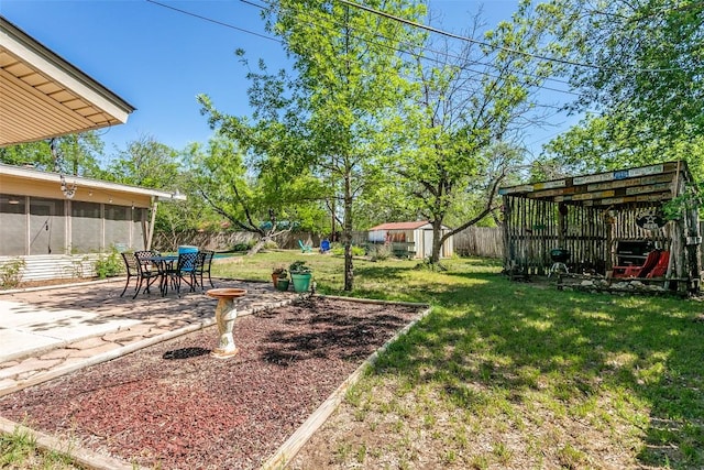 view of yard with a fenced backyard, a storage shed, an outdoor structure, a patio, and a sunroom