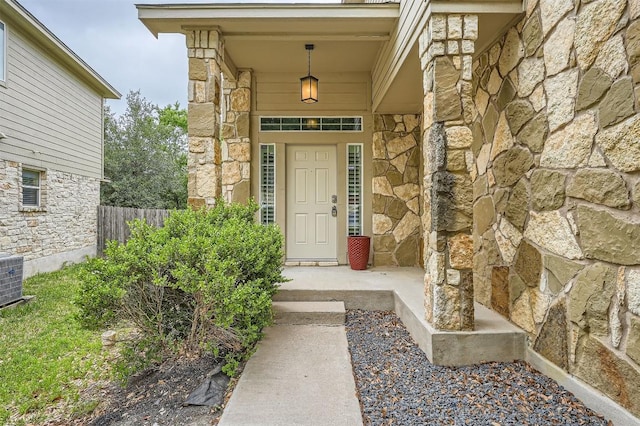 2100 Nestlewood Dr, Austin, TX 78754 - view of exterior entry featuring stone siding, fence, covered porch, and central air condition unit