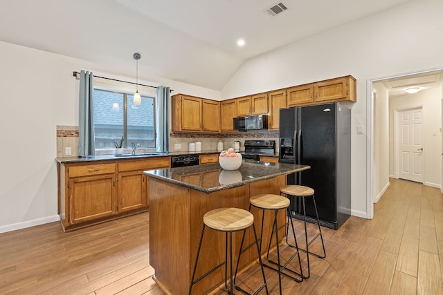 8104 Isaac Pryor Dr, Austin, TX 78749 - kitchen featuring black appliances, light wood-style flooring, backsplash, a breakfast bar, and brown cabinets