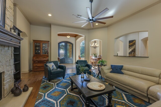 living area with arched walkways, visible vents, ceiling fan with notable chandelier, hardwood / wood-style flooring, and ornamental molding