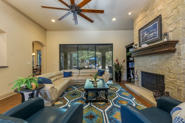 living area with a ceiling fan, wood finished floors, arched walkways, ornamental molding, and recessed lighting