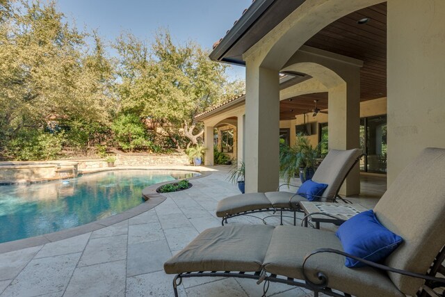 view of swimming pool with a ceiling fan, a patio area, and a pool with connected hot tub