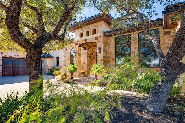 mediterranean / spanish home with stone siding, fence, and stucco siding