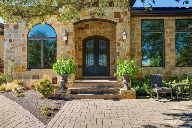 property entrance featuring stone siding and french doors