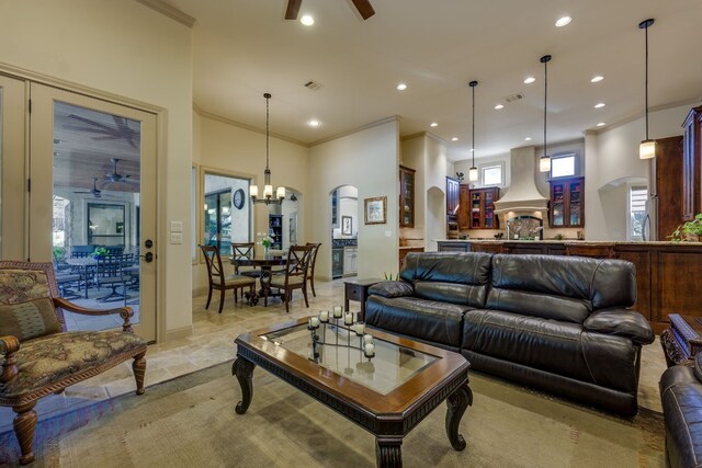 living room with recessed lighting, ornamental molding, ceiling fan with notable chandelier, and arched walkways