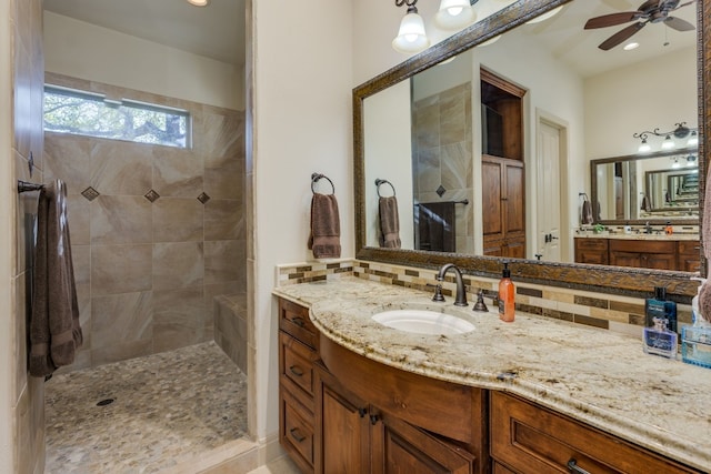 full bathroom featuring vanity, tasteful backsplash, ceiling fan, and tiled shower