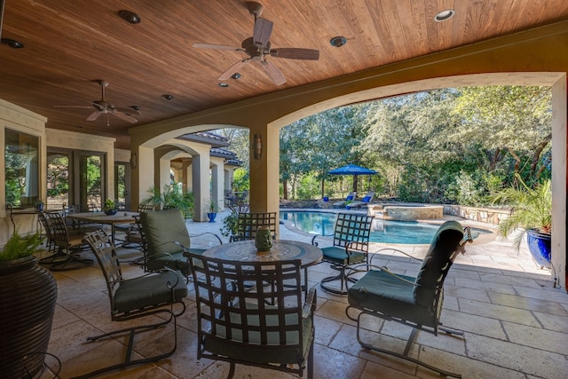 view of patio with outdoor dining area, ceiling fan, and an outdoor pool