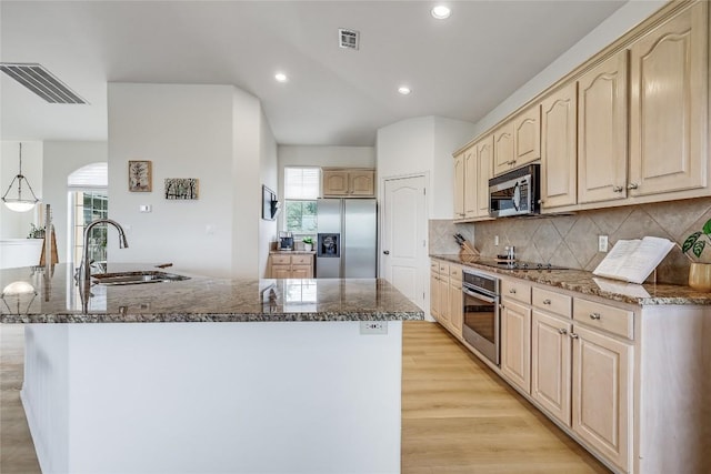 20718 Camel Back St, Lago Vista, TX 78645 - kitchen with appliances with stainless steel finishes, light brown cabinets, a kitchen island with sink, dark stone counters, and recessed lighting