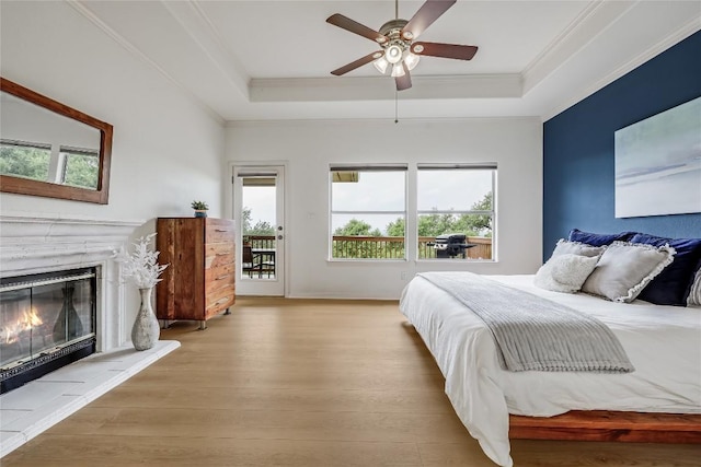 20718 Camel Back St, Lago Vista, TX 78645 - bedroom featuring wood finished floors, a raised ceiling, ornamental molding, a glass covered fireplace, and a ceiling fan