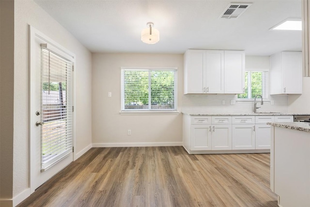 11932 Shropshire Blvd, Austin, TX 78753 - kitchen featuring light wood-type flooring, white cabinets, a sink, baseboards, and light stone countertops