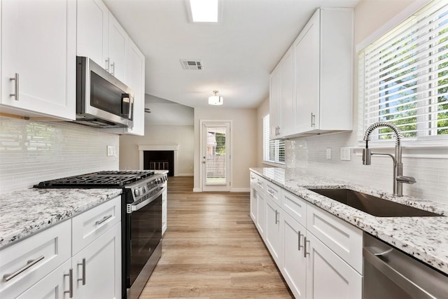 kitchen featuring visible vents, a sink, tasteful backsplash, appliances with stainless steel finishes, and white cabinetry