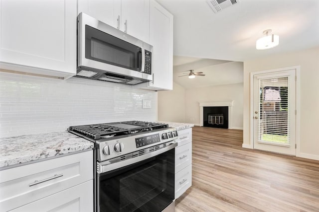 kitchen with white cabinets, stainless steel appliances, visible vents, a fireplace, and ceiling fan