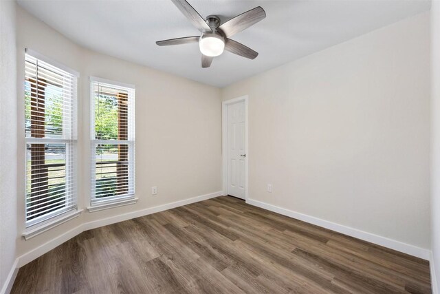 spare room with wood finished floors, a ceiling fan, and baseboards