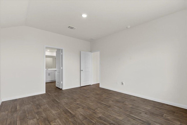 136 Medinah Ln, San Marcos, TX 78666 - unfurnished bedroom with baseboards, visible vents, lofted ceiling, ensuite bath, and dark wood-type flooring