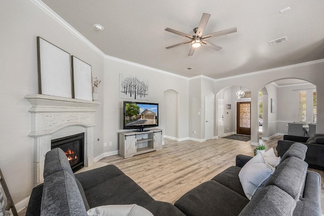 living area featuring visible vents, a ceiling fan, arched walkways, light wood-type flooring, and a fireplace