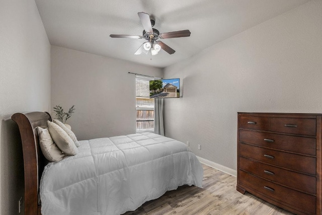 bedroom with light wood-style flooring, a ceiling fan, and baseboards