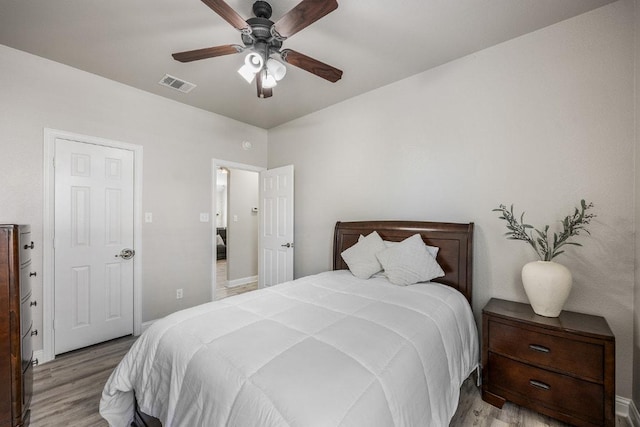 bedroom with baseboards, wood finished floors, visible vents, and ceiling fan
