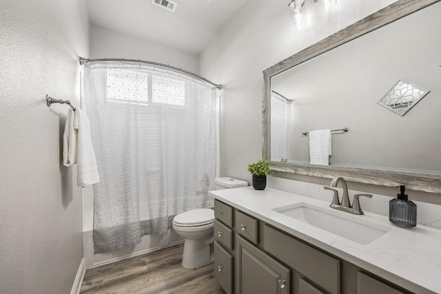 bathroom featuring toilet, visible vents, wood finished floors, shower / bathtub combination with curtain, and vanity