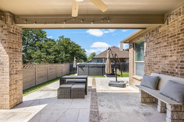 view of patio featuring a fenced backyard, a hot tub, and a ceiling fan