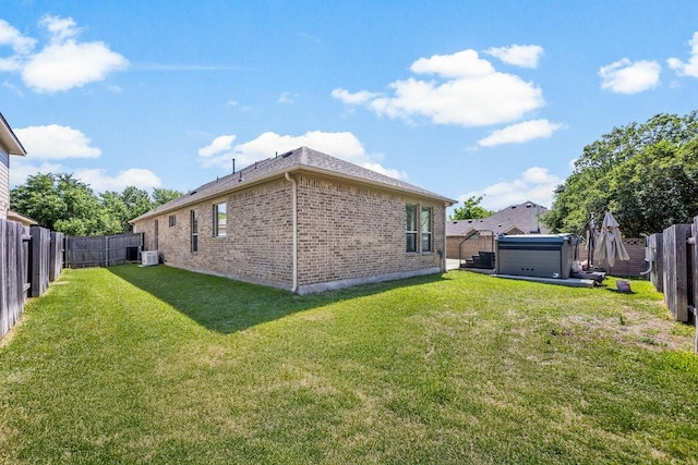 view of home's exterior with a lawn, a fenced backyard, brick siding, and central air condition unit