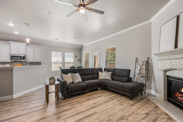 living room featuring plenty of natural light, light wood-style flooring, and ornamental molding