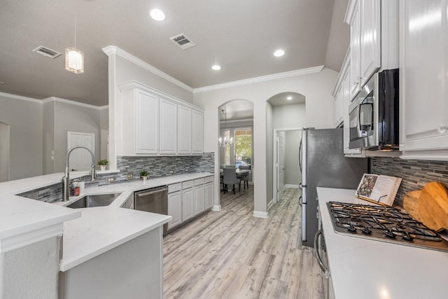 kitchen featuring a sink, arched walkways, stainless steel appliances, light wood finished floors, and visible vents