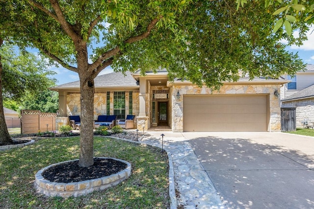 view of front of property featuring an attached garage, driveway, fence, and stone siding