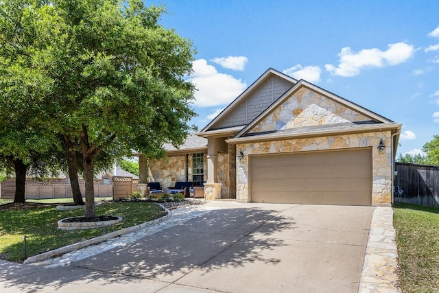 view of front of home featuring fence, driveway, stone siding, a front yard, and an attached garage