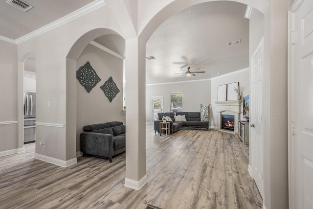living room featuring light wood finished floors, a ceiling fan, and visible vents