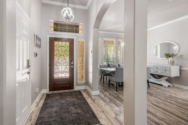 902 Fork Ridge Path, Round Rock, TX 78665 - foyer entrance with arched walkways, light wood finished floors, a chandelier, crown molding, and baseboards