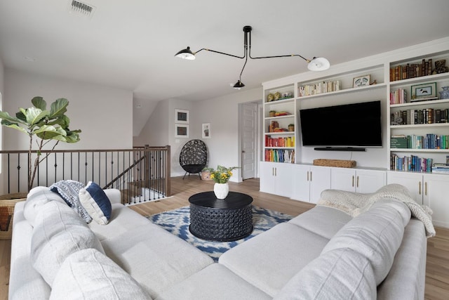 living area featuring visible vents, wood finished floors, and baseboards
